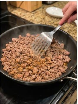 Ground beef browning in a skillet for loaded queso burger potato cups